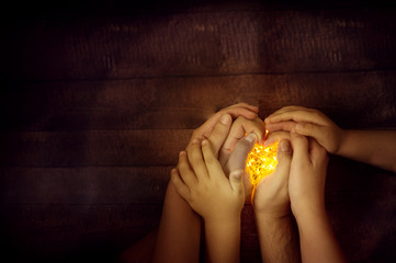 christmas mood top view family hands holding lights: mom, dad and kid. wooden background