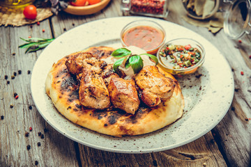 two pieces of of grilled pork with herbs on a paper on an old table top view horizontal close-up