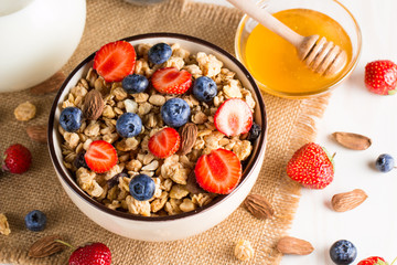 Healthy breakfast concept with oat flakes and fresh berries on rustic background. Food made of granola, muesli. Healthy banana smoothie with blackberries, muslie, strawberries, blueberries and honey.
