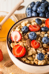 Healthy breakfast concept with oat flakes and fresh berries on rustic background. Food made of granola, muesli. Healthy banana smoothie with blackberries, muslie, strawberries, blueberries and honey.