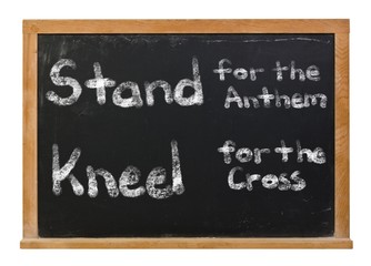 Stand for the anthem, kneel for the cross written in white chalk on a black chalkboard isolated on white