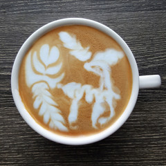 Top view of a mug of latte art coffee on timber background.