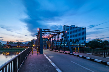 The historical iron bridge at Chiangmai city skyline at Ping river at dusk. Chiangmai , Thaland. Long exposure photograph.