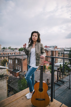 Street music. Young girl with acoustic guitar on city roof. Freedom, leisure, youth lifestyle, young bard and composer concept