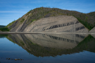 Outcrop of layered rocks in a steep Bank of the river. The Indigirka river, Sakha Republic, Russia.