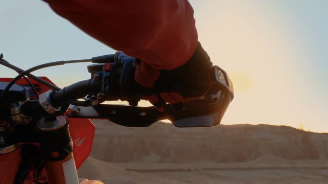  Close-up of the Motorcyclist's Hand Twisting Throttle Handle While Standing on the Scenic Quarry Off-Road Terrain in the Sunset.Shot on RED EPIC-W 8K Helium Cinema Camera.