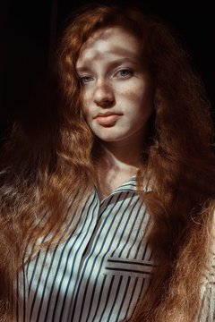 Beautiful Red Haired Model With Freckles And Long Hair. Woman With Shadow On Her Face