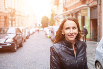 Obraz premium Young smiling woman walking on european town street. Happy tourist girl strolling in cobbled road in summer vacations