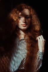 Pretty red haired model with freckles and long hair. Woman with shadow on her face © vpavlyuk