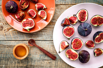 Plate of fresh blue figs on wooden background top view