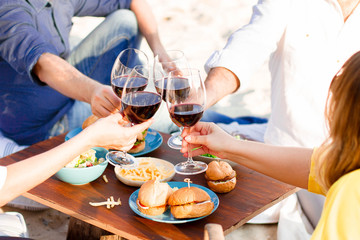 Obraz na płótnie Canvas Hands Friends toasting red wine glass and having fun outdoors.