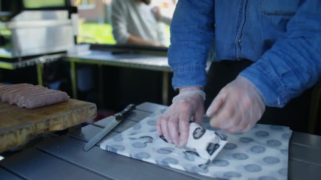  Street food vendor making hot dogs for customers at summer festival.