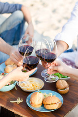 Fototapeta na wymiar Hands Friends toasting red wine glass and having fun outdoors.