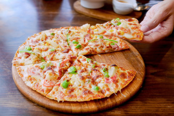Hands taking slices of italian pizza on wooden board