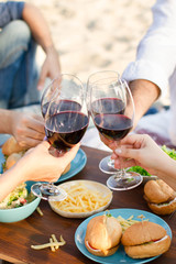      Hands Friends toasting red wine glass and having fun outdoors.
