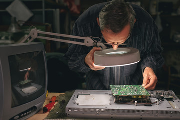 Male technician inspecting defective circuit board
