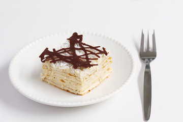 isolated slice of decorated with chocolate napoleon cake, served on white plate