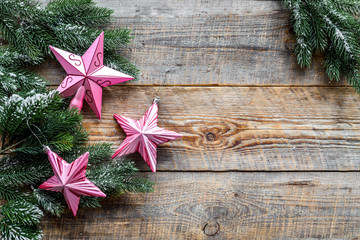 Christmas toys. Pink stars near pine branches on wooden background top view copyspace