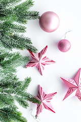 Christmas toys. Pink stars and balls near pine branches on white background top view