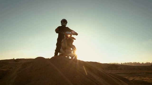 Professional Motocross Rider on FMX Motorcycle Stands on the Sand Dune and Overlooks Whole Extreme Off-Road Terrain that He Gonna Ride Today. Shot on RED EPIC-W 8K Helium Cinema Camera.
