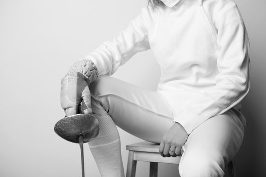 Close-up of female fencer sitting and holding sabre