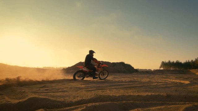 Following Shot of the Professional Motocross Driver Turning on His FMX Motorcycle on the Extreme Off-Road Terrain Track. Shot on RED EPIC-W 8K Helium Cinema Camera.