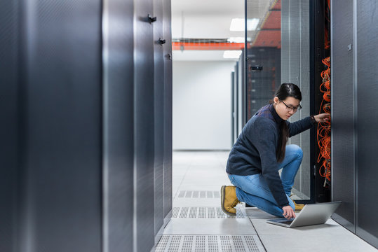 Female technician working on server in data center