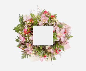 Creative layout made of flowers and leaves with paper card note. Flat lay