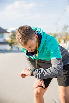 A fit young male runner checking his watch