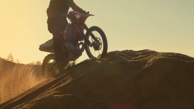 Low Angle Shot of the Professional Motocross Motorcycle Rider Standing on the Path of the Off-Road Track. It's Sunset. Shot on RED EPIC-W 8K Helium Cinema Camera.