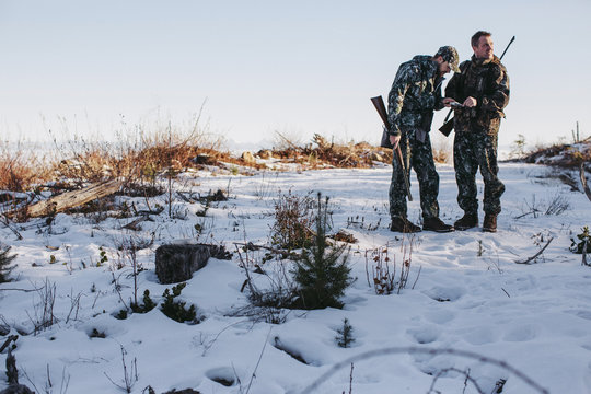 Two men hunting together using gps technology map on mobile phone