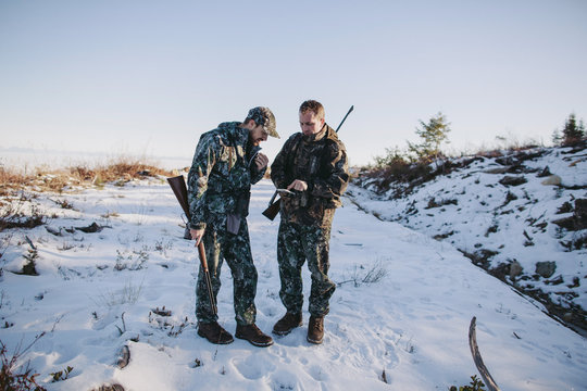 Two men hunting together using gps technology map on mobile phone