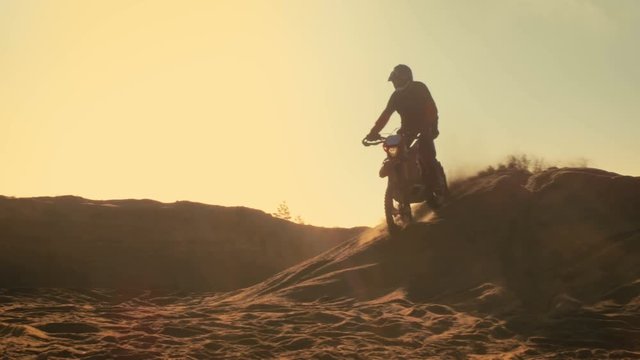 Long Shot of the Professional Motocross Motorcycle Rider Drives Over the Dune and Further Down the Off-Road Track.  Shot on RED EPIC-W 8K Helium Cinema Camera.