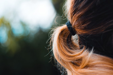 Close-Up Of Beautiful Girl With Orange Colored Hair Held In Ponytail Looking Away From The Camera