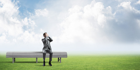 Young man in summer park on bench do not want to see anything