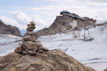 Balanced stone pyramid with Dachstein cable car station in background