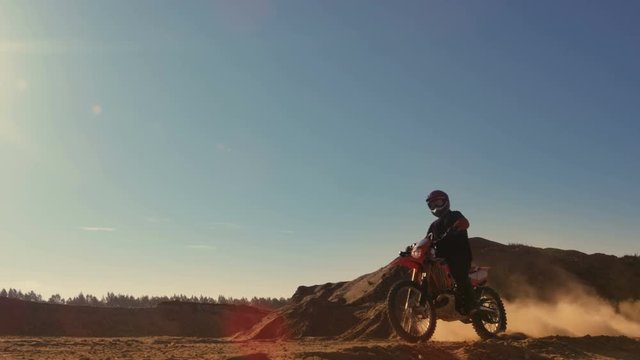 Long Shot of the Professional Motocross FMX Motorcycle Rider Drives Over the Dune and Further Down the Off-Road Track.  Shot on RED EPIC-W 8K Helium Cinema Camera.