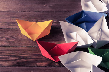 Business leadership concept with white and color paper boats on 