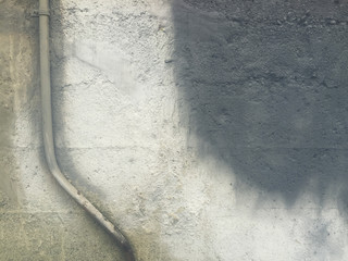 Metal utility pipe and grey paint covering graffiti on concrete wall