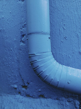 Close up of painted blue gutter pipe and wall