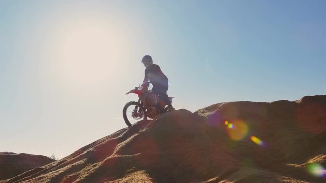 Professional Motocross Motorcycle Rider Drives Over the Dune and Further Down the Off-Road Track. He's Riding on the Deserted Industrial Quarry. Shot on RED EPIC-W 8K Helium Cinema Camera.