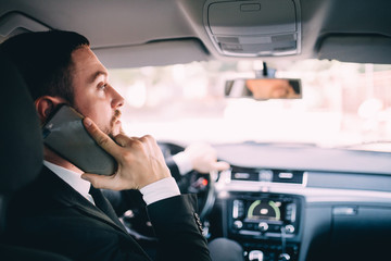 Business Man using his phone while driving the car