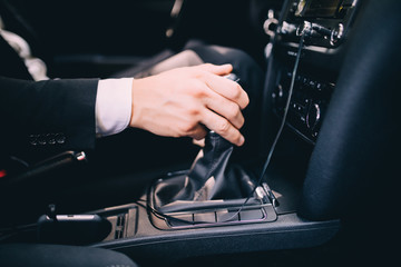 Businessman in a business suit in the car changes gear