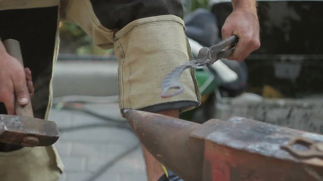 Blacksmith is hammering a red-hot piece of iron