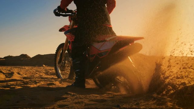 Back View Footage of the Professional Rider on the FMX Dirt Bike Twisting Full Throttle Handle and Digging into the Sand with His Back Wheel.Shot on RED EPIC-W 8K Helium Cinema Camera.