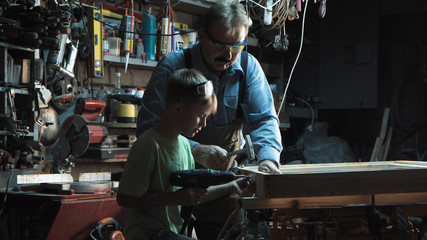 Fototapeta na wymiar Adult carpenter man and grandson make a product from wood and screws with a screwdriver.