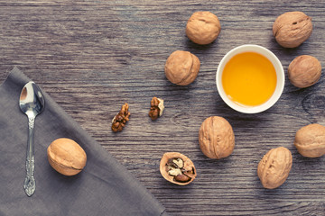 Honey with nuts on a wooden surface with a napkin and a spoon. View from above