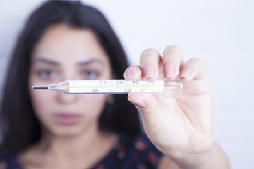 sick woman holding thermometer