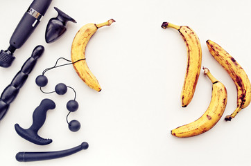 A variety of sex toys (anal balls, dildo, vibrator, prostate massager, butt plug) and bananas on a...