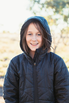 tween girl in a warm coat outside in a sunny field